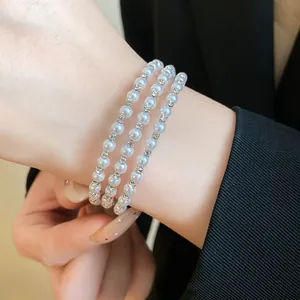 Detailed macro view of a three-layer bracelet with white pearls and sparkling rhinestones
