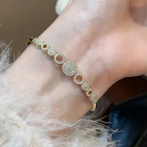 Primer plano de un brazalete geométrico chapado en oro de 14K con circonitas
