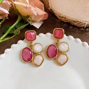 Vintage palace style geometric resin drop earrings with gold frames on a white plate