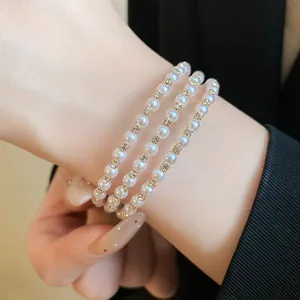 Detailed close-up of a elegant three-row pearl and rhinestone bracelet for women.