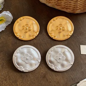 Macro view of vintage style gold and silver coin stud earrings with floral pattern