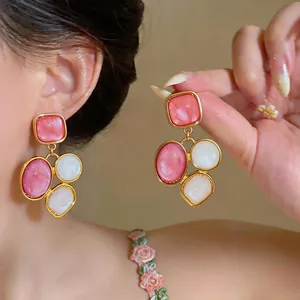 Close-up of elegant vintage geometric resin drop earrings featuring pink and white stones