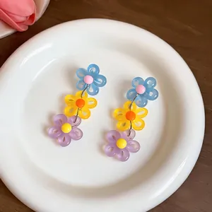 Detailed macro view of vibrant colorful dopamine daisy earrings on a white plate