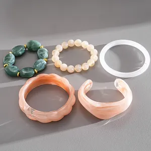 Detailed view of five unique acrylic geometric bracelets in marbled green and peach