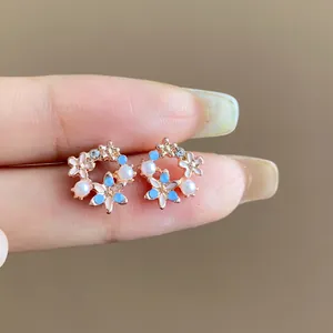 Primo piano di raffinati orecchini a lobo con fiori e perle dai toni blu e bianchi eleganti.