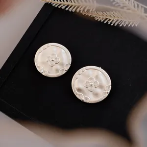 Detailed close-up of vintage 18k gold-plated round stud earrings with embossed texture.