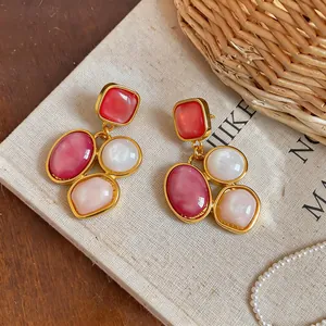 Close-up of vintage geometric resin earrings with red and pink inlays on linen background