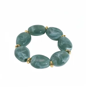 Minimalist acrylic bracelet with irregular marbled green oval beads and gold spacers.