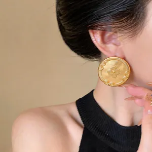 Detailed macro shot of vintage 18k gold plated round earrings with embossed floral pattern