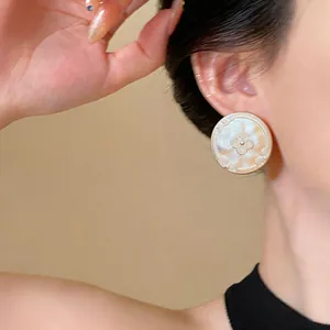 Detailed shot of vintage 18k gold plated circular earrings with floral engraving on a model