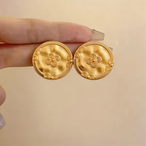 Close-up detail of vintage 18k gold-plated round earrings with embossed flower pattern