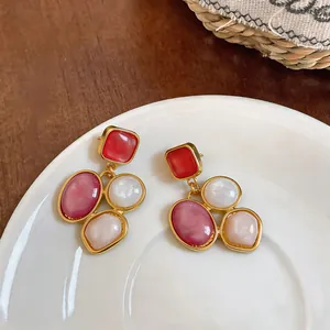 Detailed view of vintage geometric earrings with colorful resin stones and gold finish.