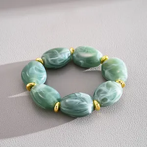 Detailed view of green marble acrylic bracelet featuring gold oval geometric beads