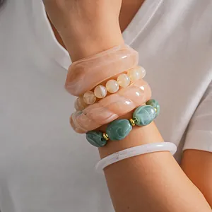 Detailed view of 5 unique acrylic bracelets with marble textures on a female wrist