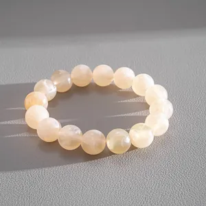 Macro view of creamy marbled acrylic beaded bracelet on a textured grey background