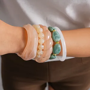 Close-up detail of layered acrylic geometric bracelets in peach and green marble finish