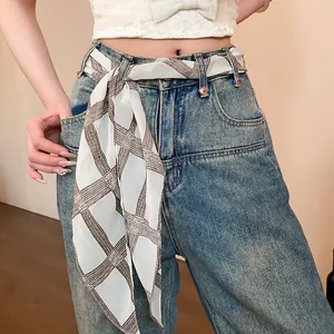 Detail of a retro printed chiffon scarf used as a stylish belt on blue jeans