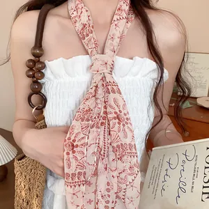 Detail view of a retro floral chiffon scarf tied as a necklace with a white top.
