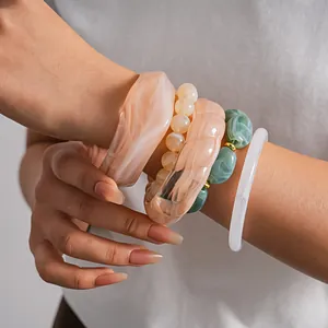 Close-up detail view of stacked acrylic irregular geometric bangles and beaded bracelets