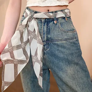 Detail shot of a vintage plaid chiffon scarf tied as a decorative belt on denim jeans