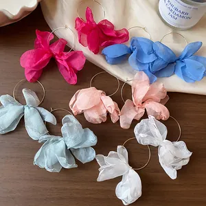 Detailed view of colorful chiffon flower hoop earrings on elegant prop background