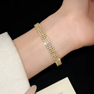 Primer plano de una lujosa pulsera dorada con varias filas de pedrería en una muñeca femenina