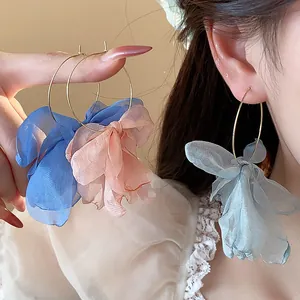 Close-up detail of oversized fabric flower hoop earrings in romantic blue and pink tones