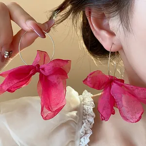 Detailed view of oversized hoop earrings with elegant magenta chiffon bow decoration