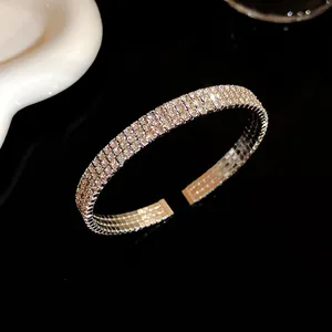 Primer plano de un brazalete abierto brillante con varias filas de pedrería plateada elegante