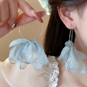 Macro detail of elegant light blue fabric petal hoop earrings worn by an Asian model