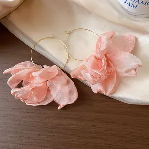 Detail of sweet resort-style pink fabric flower hoop earrings on soft draped fabric