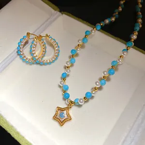 Close-up of vintage pearl and blue stone necklace with gold star pendant and hoop earrings