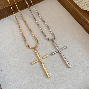 Macro detail view of vintage gold and silver metal cross pendants with ball chains on fabric.