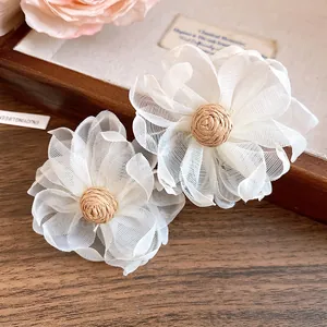 Dettaglio ravvicinato di orecchini a fiore in chiffon bianco con centro in rafia