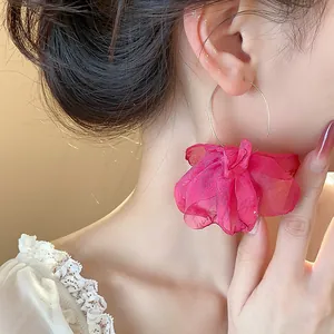 Close-up detail of large gold hoop earring with bright pink fabric flower knot decoration