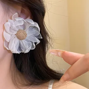 Dettaglio di orecchino a fiore in chiffon bianco con centro in rafia