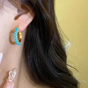 Detailed view of vintage gold hoop earrings with turquoise beads and shiny zircons