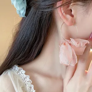 Close-up of sweet pink fabric flower hoop earring on model, elegant vacation style.