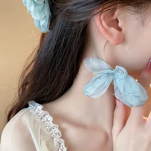 Close-up of sweet light blue organza bow gold hoop earrings for a vacation look