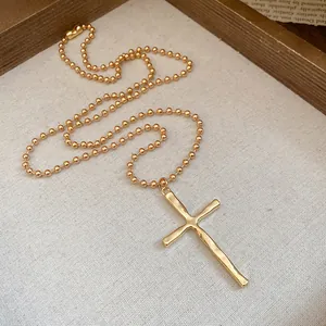 Detailed view of the vintage gold cross pendant with metallic ball chain necklace
