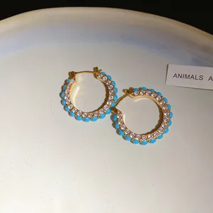 Detailed view of vintage gold hoop earrings with sparkling zircons and blue beads