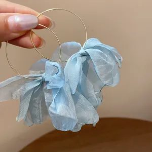 Close-up of light blue mesh flower detail on elegant gold hoop earrings