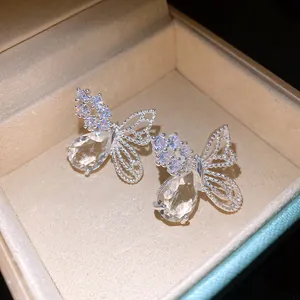 Macro dettaglio di orecchini a farfalla in argento con pietra di zircone a goccia lucente