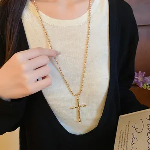 Detailed macro view of a vintage gold cross pendant necklace worn by a female model