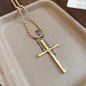 Detailed close-up of a vintage gold cross pendant with a beaded chain necklace