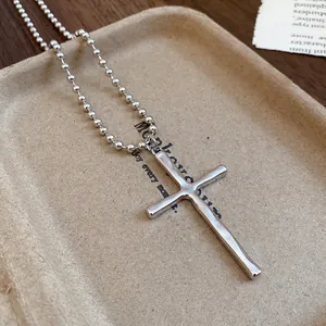 Detailed macro view of a vintage silver cross pendant on a stylish beaded chain necklace