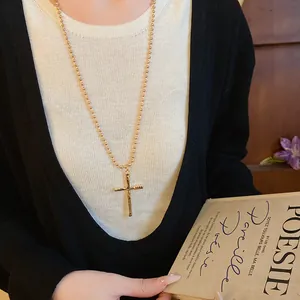 Detailed view of a stylish vintage gold cross pendant necklace on a long ball chain necklace