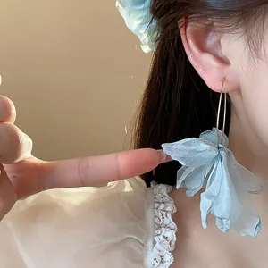 Detailed close-up showing light blue fabric flower hoop earrings worn by a model
