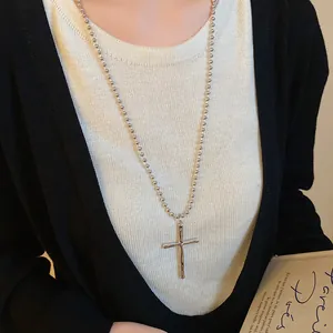 Close-up of vintage silver cross pendant necklace with ball chain on model.