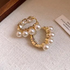 Französische Vintage Gold Creolen mit Perlen und Kristallen auf beigem Hintergrund.